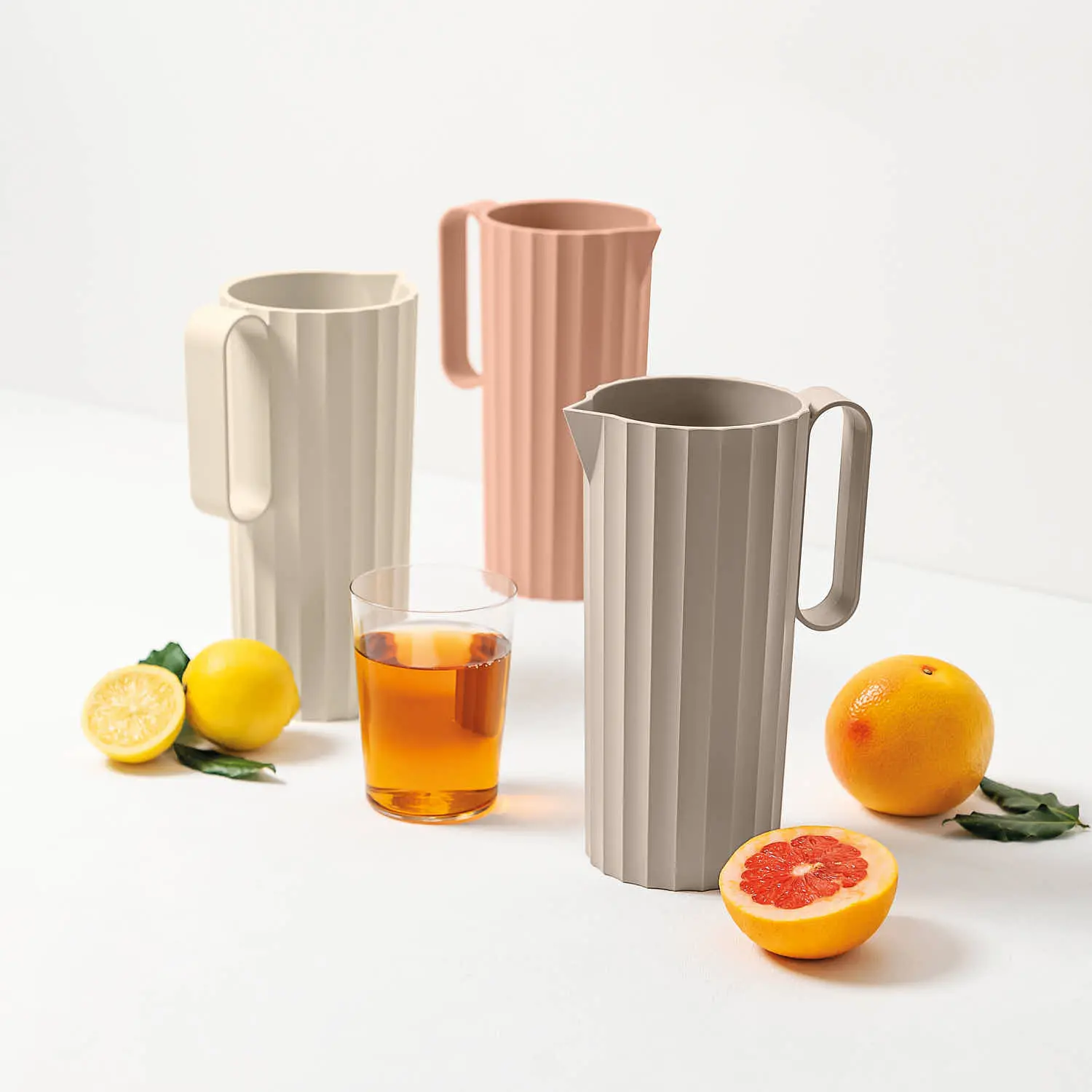 Caraffe Hydria Blim Plus in Moka Grey, Brown Sugar e Pink Sand, con succo e agrumi in tavola