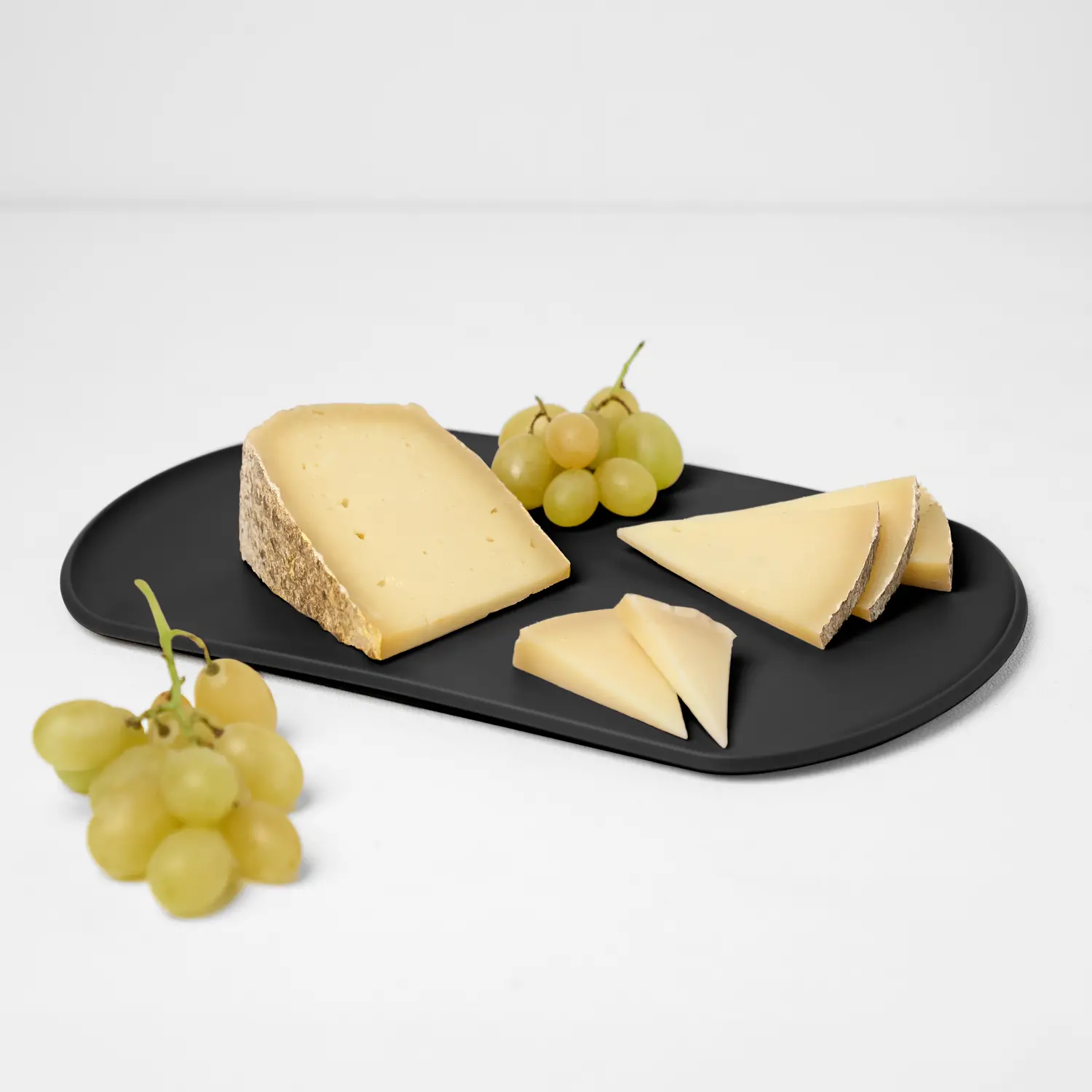 Skateboard Blim Plus in Carbon Black: tagliere con formaggio e uva su sfondo chiaro.