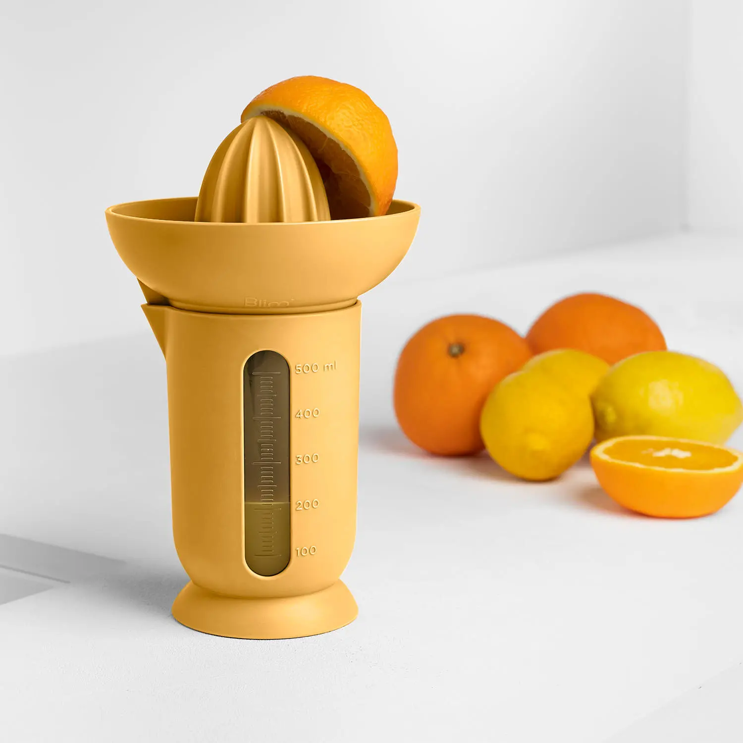 Ufo Blim Plus: citrus juicer with graduated carafe up to 500 ml in Desert color, with oranges in the background